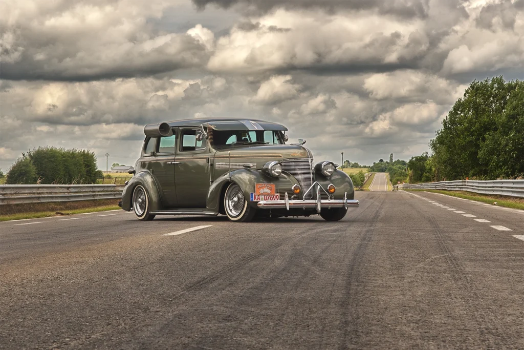 Berline américaine des années 40 roulant sous un ciel nuageux, Hot Rod Custom Show Chimay