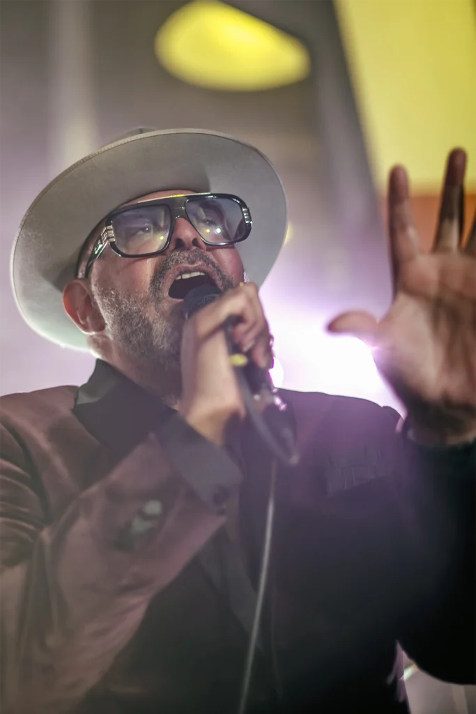Barry Adamson chante, main levée sous la lumière, concert BXL Central chez PIAS, Bruxelles. Photo Didier Vaneesbeck
