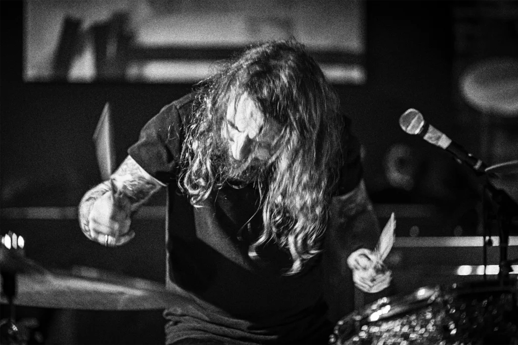 Le batteur de Giac Taylor en noir et blanc, penché sur sa batterie, concert à Forest. Photo Didier Vaneesbeck