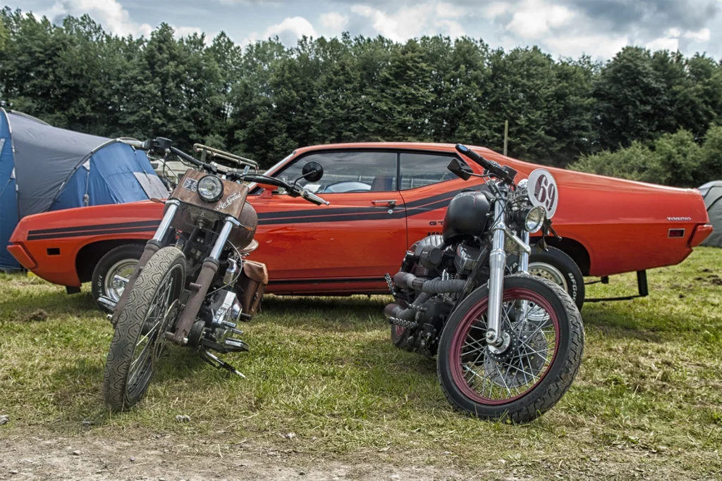 Choppers garés devant une muscle car rouge au Hot Rod Custom Show de Chimay