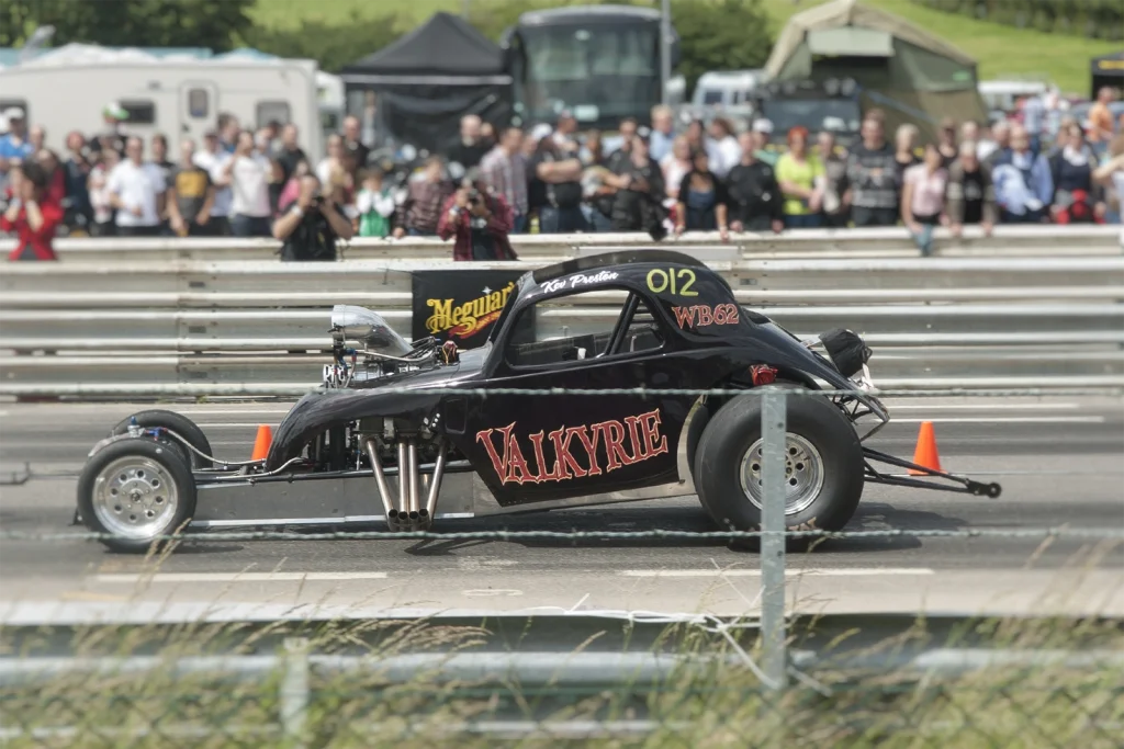 Hot rod noir lancé sur la piste devant le public, drag race au Hot Rod Custom Show de Chimay