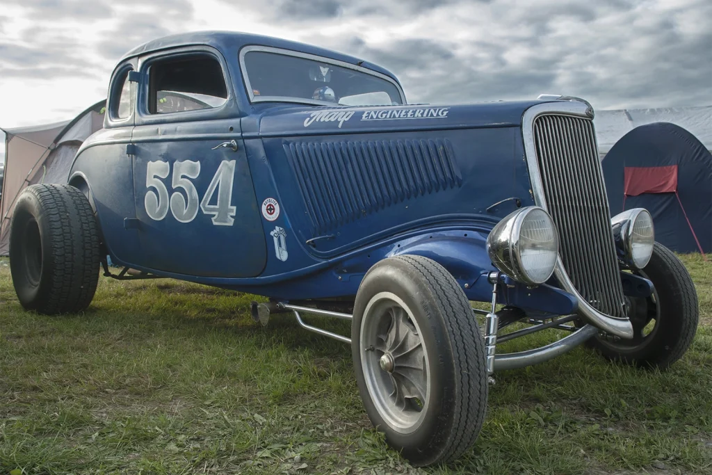 Coupé hot rod bleu numéro 554 garé sur l'herbe au Hot Rod Custom Show de Chimay