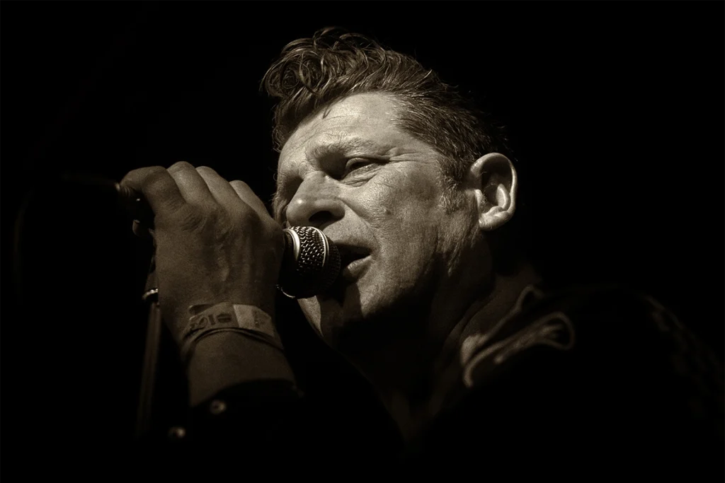 Chanteur rockabilly au micro en noir et blanc, concert au Hot Rod Custom Show de Chimay