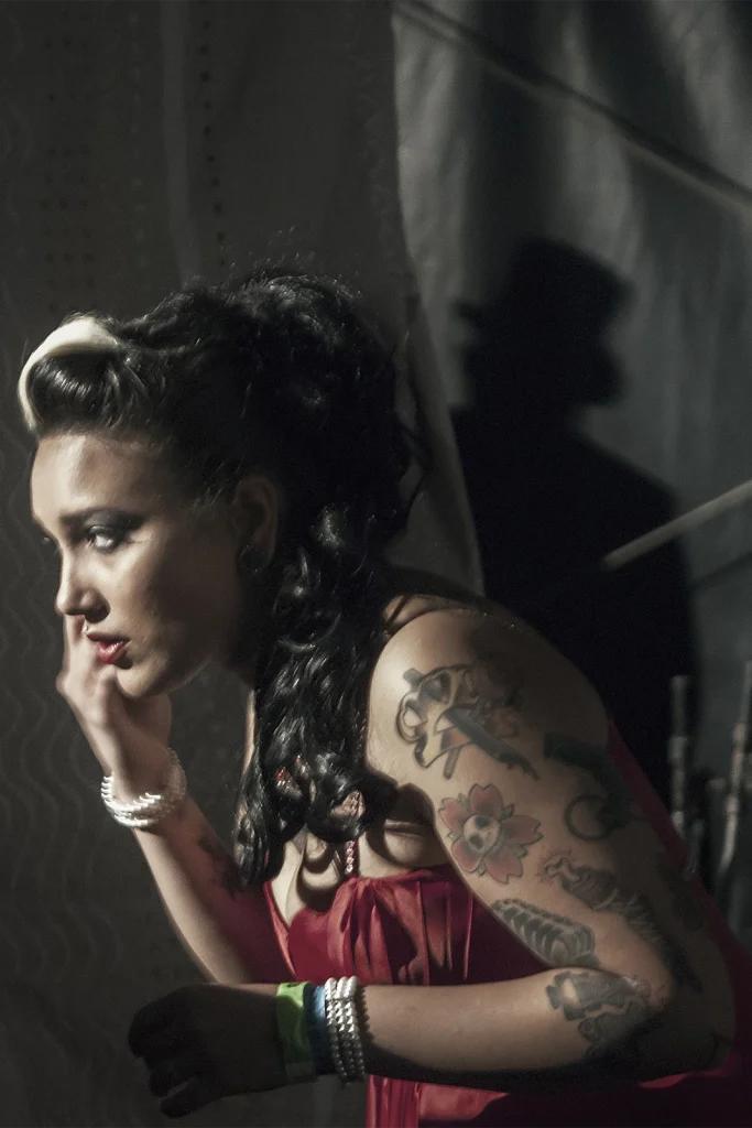 Pin-up tatouée pensive en coulisses au Hot Rod Custom Show de Chimay
