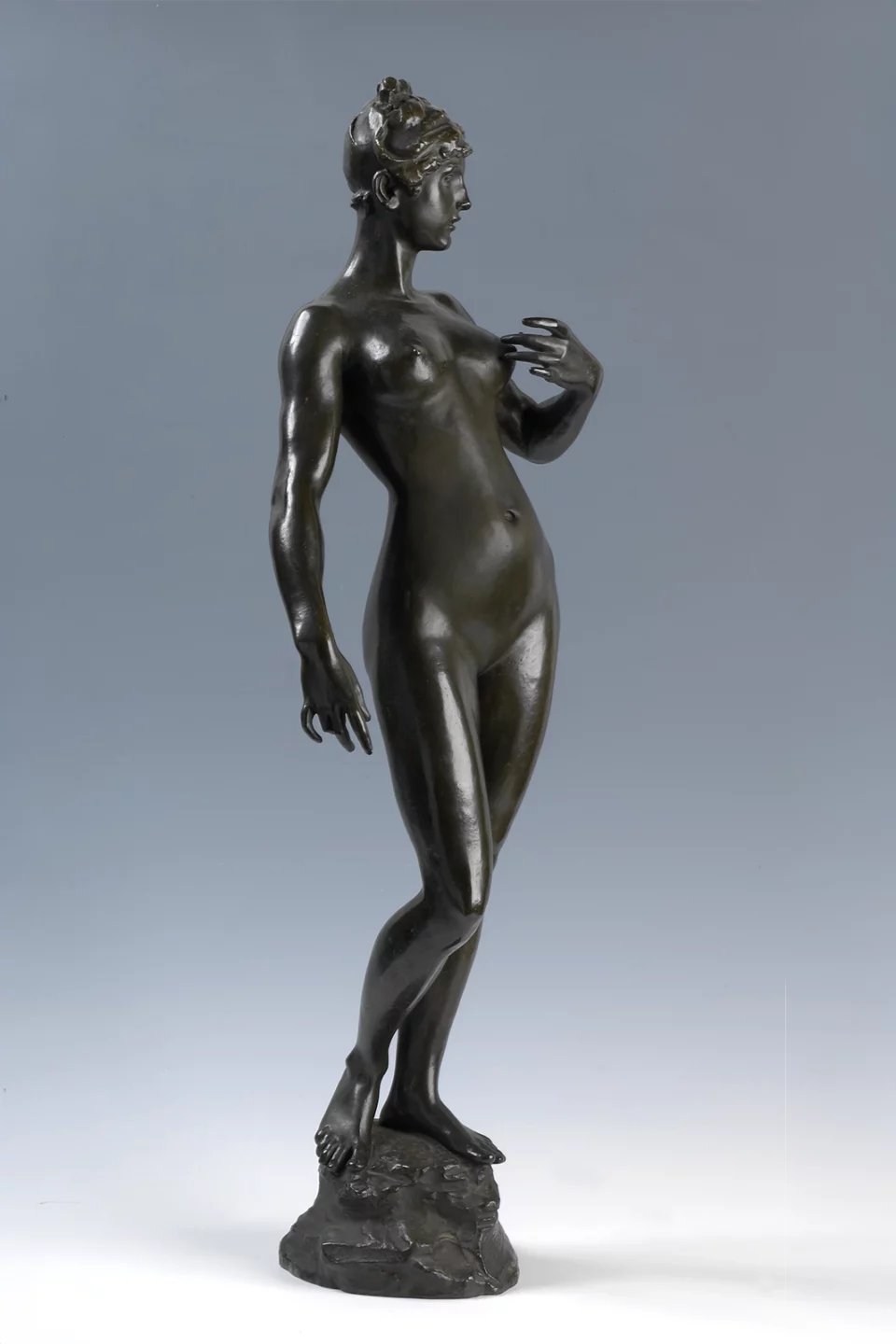 Statuette en bronze d'une femme debout, photographiée sur fond gris