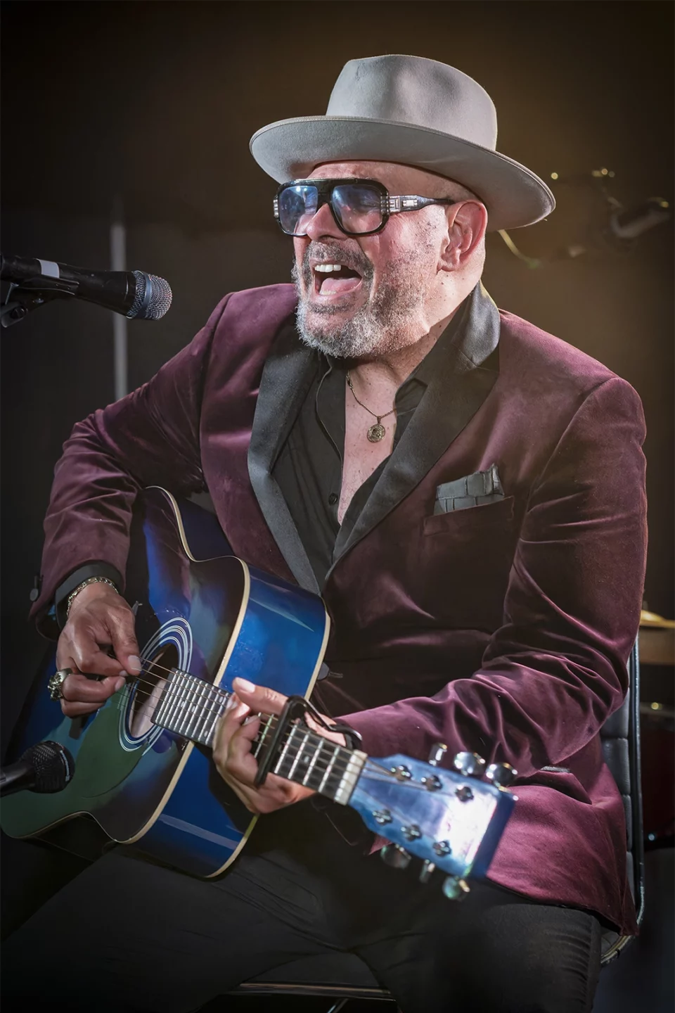 Barry Adamson, chapeau et lunettes noires, éclat de rire guitare en main, en concert à Bruxelles