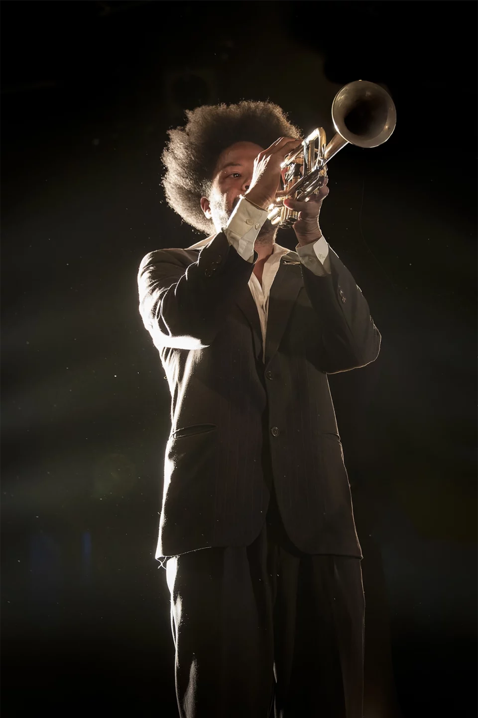 Trompettiste en costume éclairé dans l'obscurité, en concert à La Cartonnerie de Reims