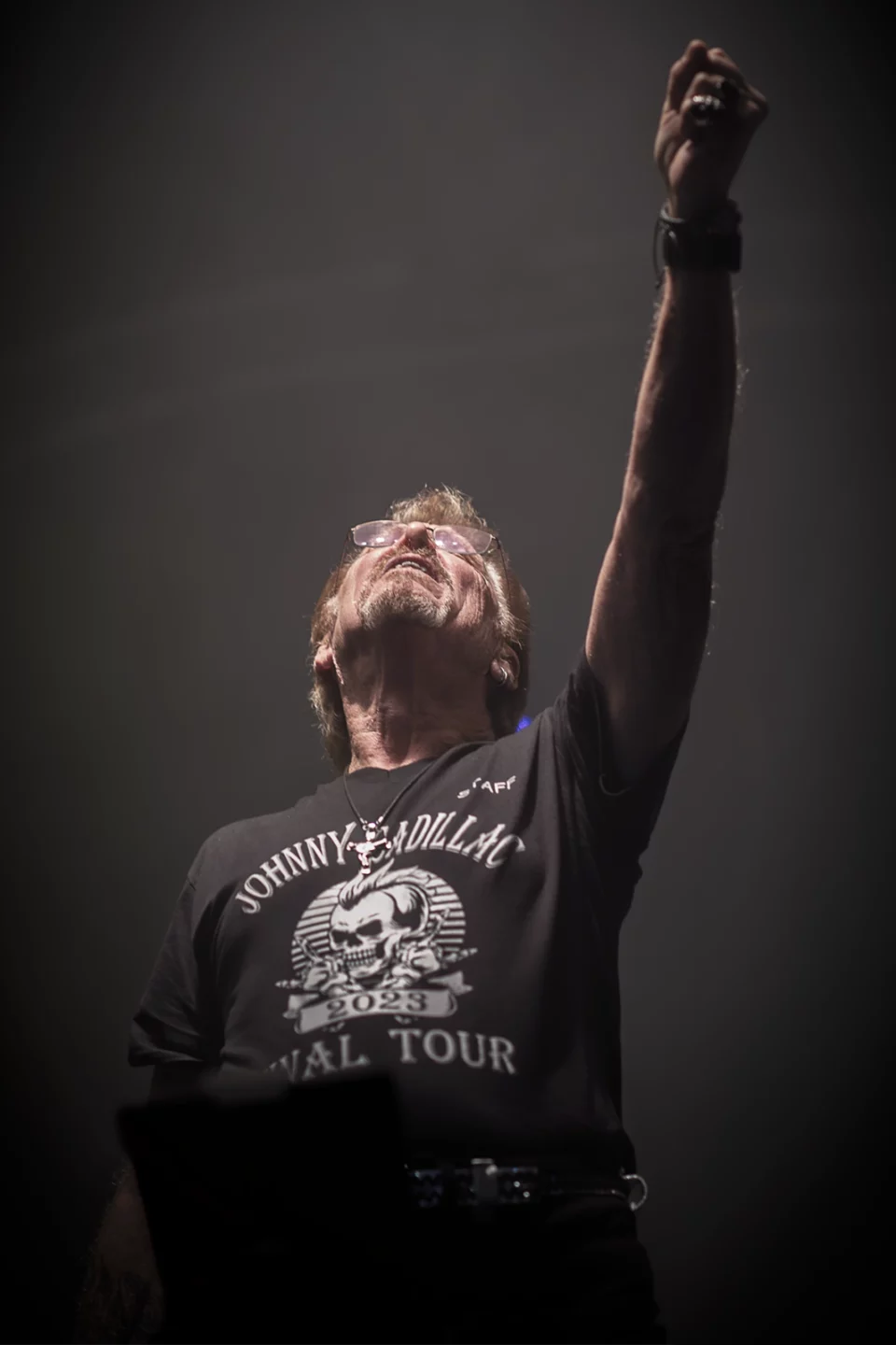 Johnny Cadillac levant le poing vers les projecteurs, en concert à Namur