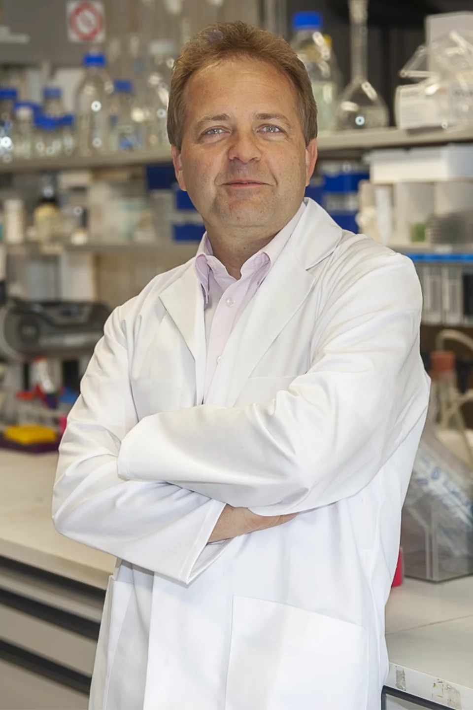 Portrait professionnel d'un chercheur en blouse blanche, bras croisés, dans son laboratoire
