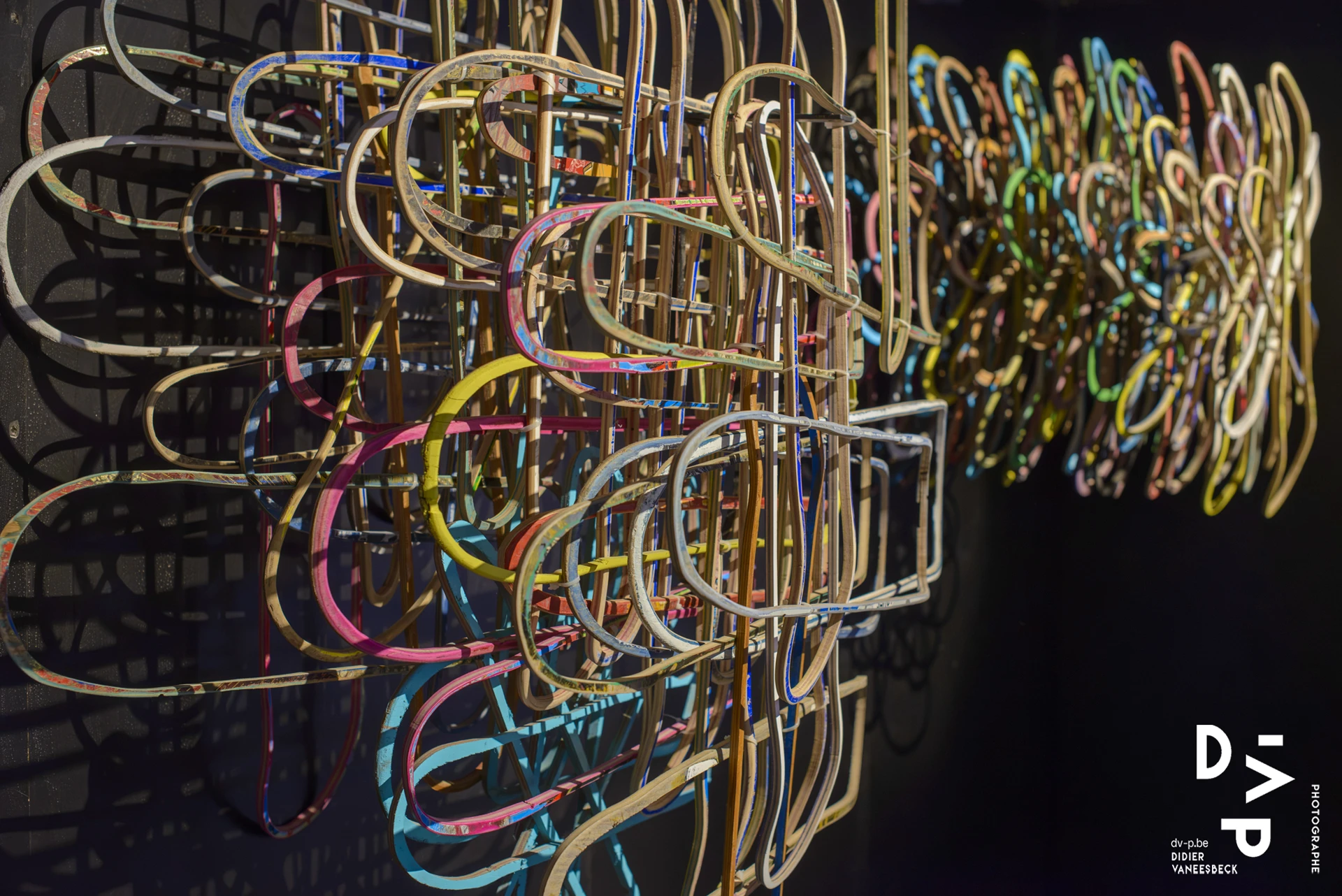 Installation de tubes lumineux colorés entrelacés sur fond noir – Strokar Inside, Bruxelles 2018