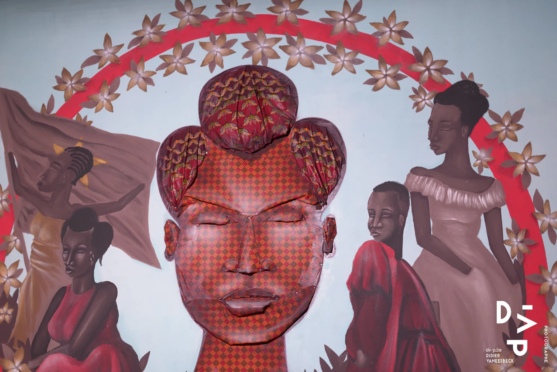 Fresque d'un visage stylisé rouge entouré de silhouettes féminines et de motifs floraux – Strokar Inside, Bruxelles 2018