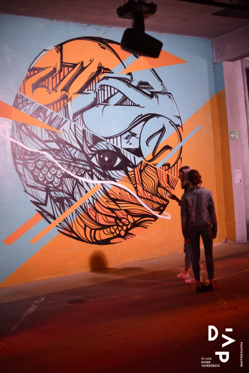Visiteur devant une œuvre circulaire calligraphiée sur fond orange – Strokar Inside, Bruxelles 2018