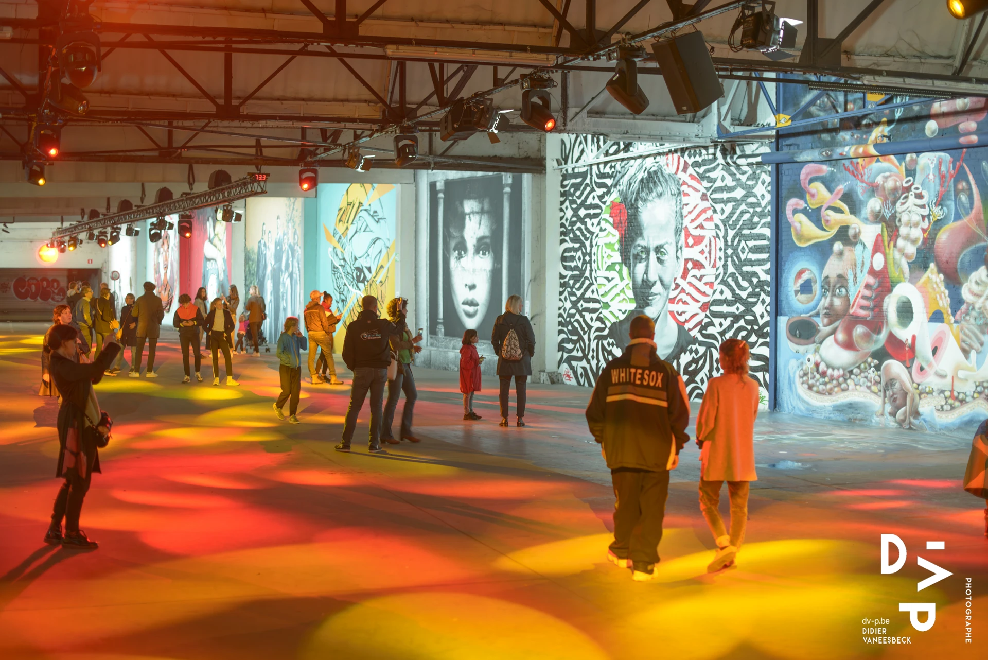 Visiteurs dans la grande halle sous des éclairages colorés – Strokar Inside, Bruxelles 2018