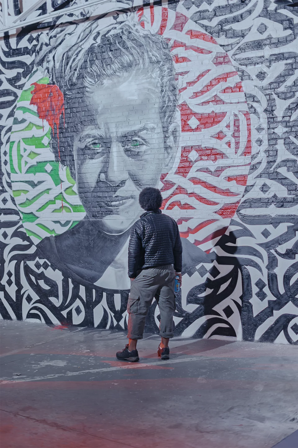 Enfant de dos devant une grande fresque street art en noir, blanc et rouge
